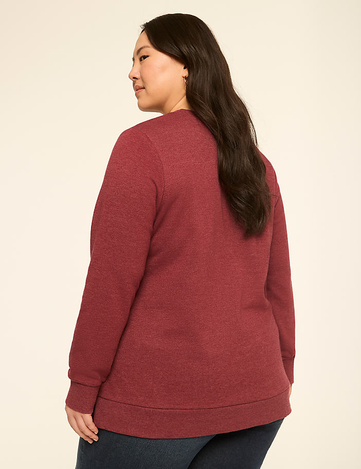 A woman in a maroon sweatshirt stands against a plain, light-colored background.