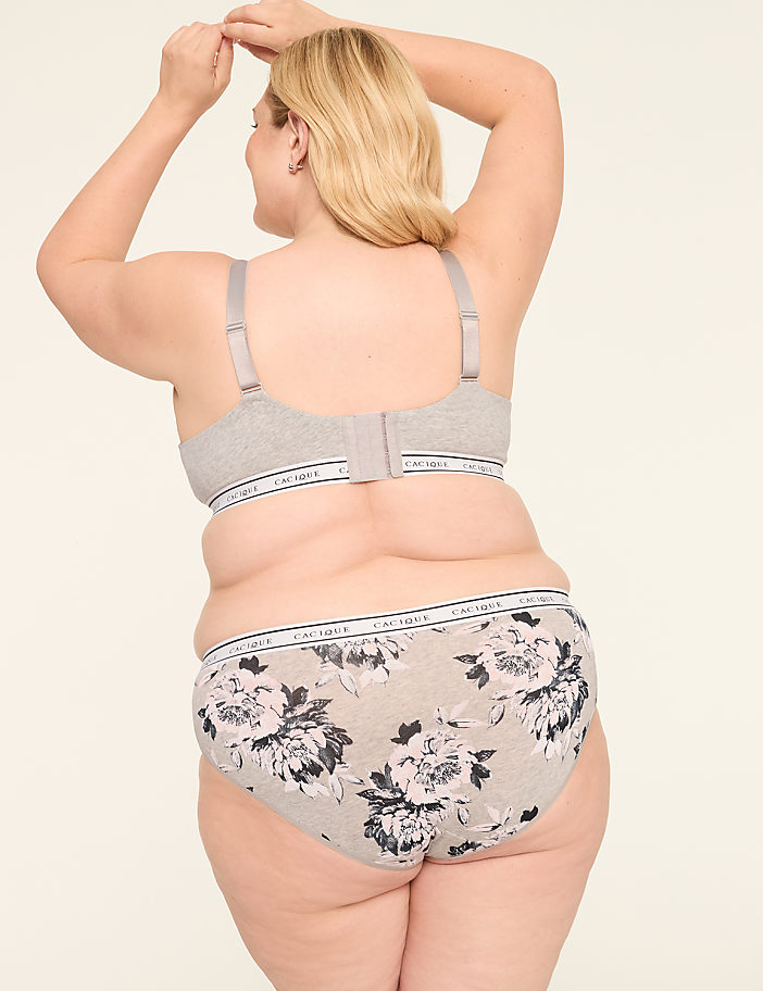 A woman from behind, wearing a grey bra and floral patterned underwear, stands against a plain, light-colored background.