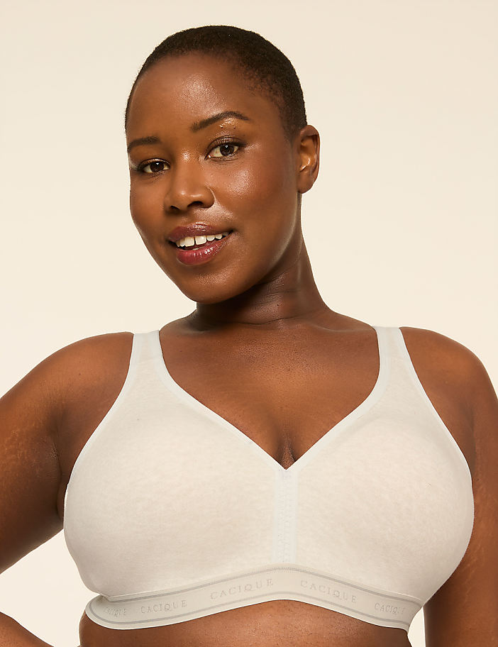 A smiling woman with short hair wears a light-colored bra against a plain, light background.