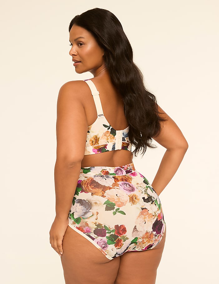 A woman in a floral bikini stands against a plain, light-colored background.