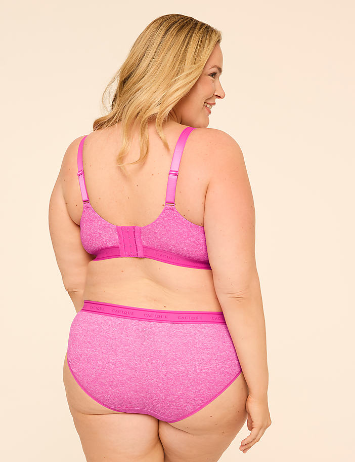 A woman in a pink bra and underwear stands against a plain, light-colored background.