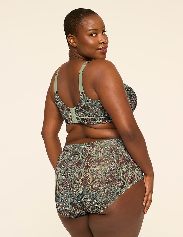 A woman in a paisley-patterned bra and underwear stands against a plain, light-colored background.