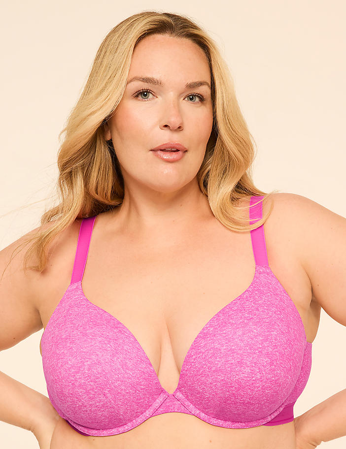 A woman with blonde hair and fair skin wears a pink bra against a plain, light-colored background.