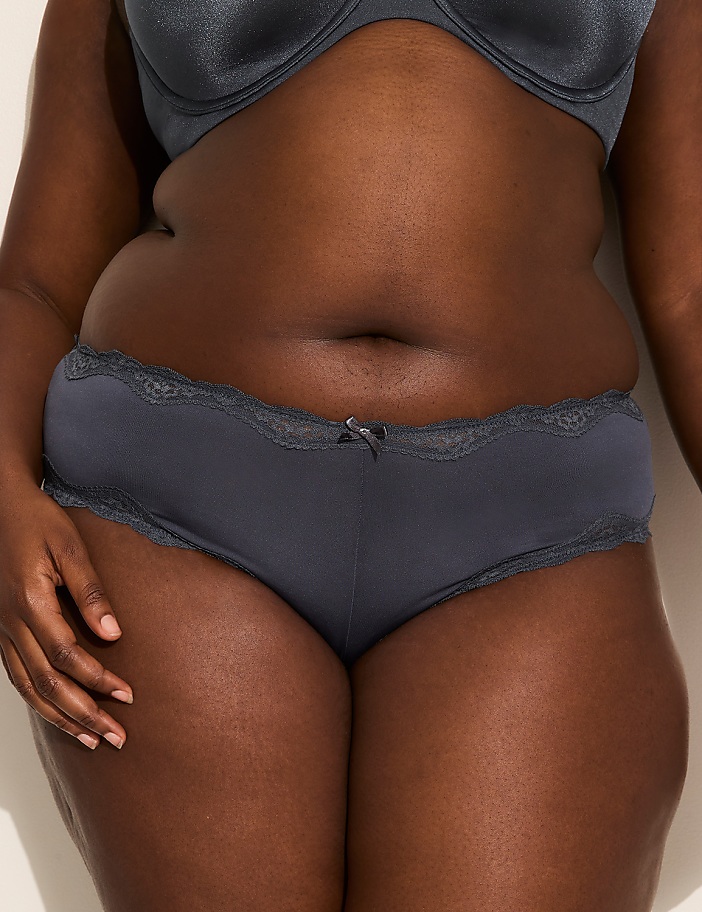 A person's torso is shown from the waist down, wearing dark grey underwear with lace trim, against a plain, light-colored background.