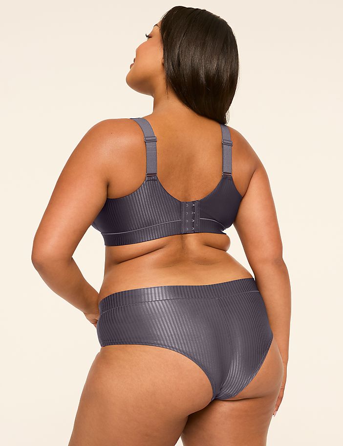 A woman in a grey ribbed bra and underwear stands with her back to the viewer against a plain, light background.