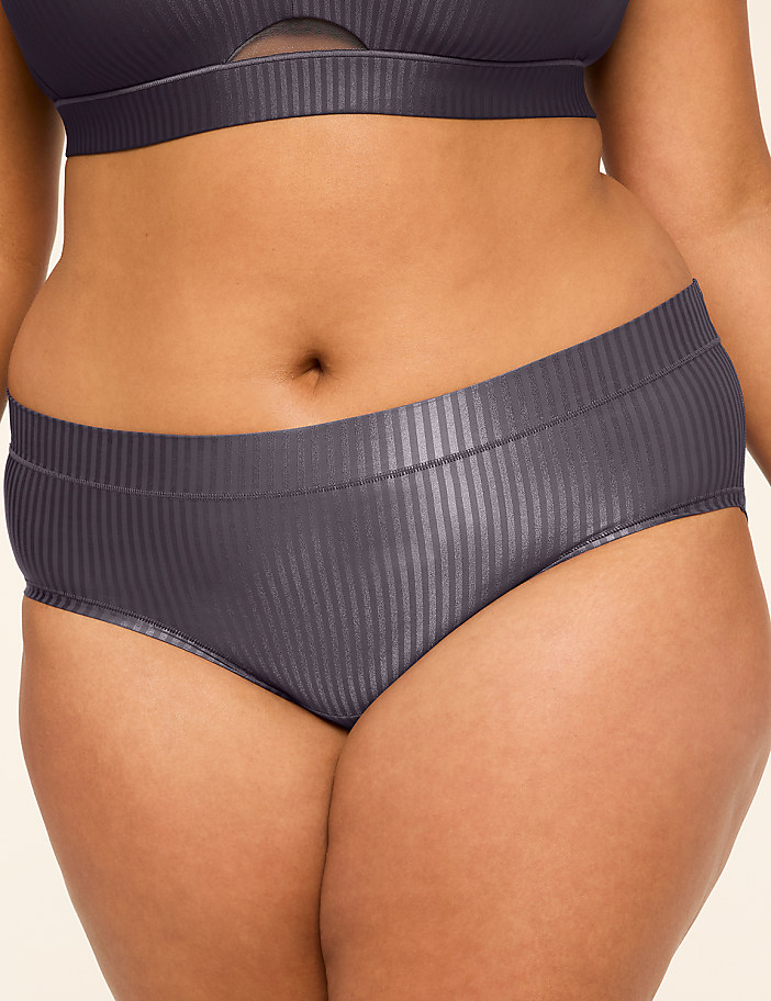 A person's midsection is shown in the foreground, wearing ribbed grey underwear, against a plain, light-colored background.
