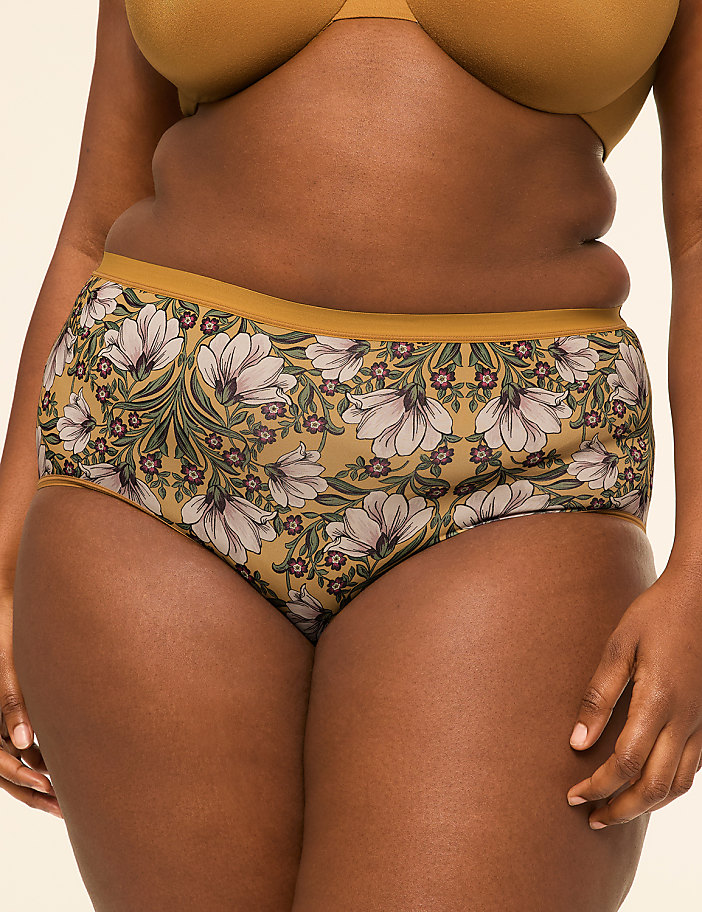 A person wears floral patterned underwear in the foreground against a plain, light-colored background.