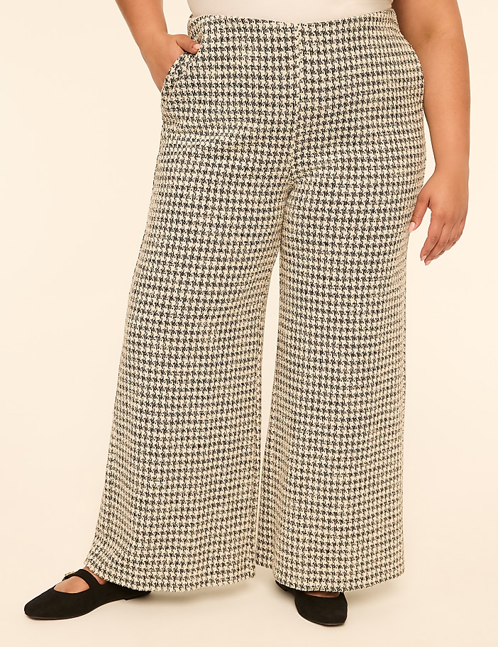 A person wearing wide-leg houndstooth pants stands against a plain, light-colored background.