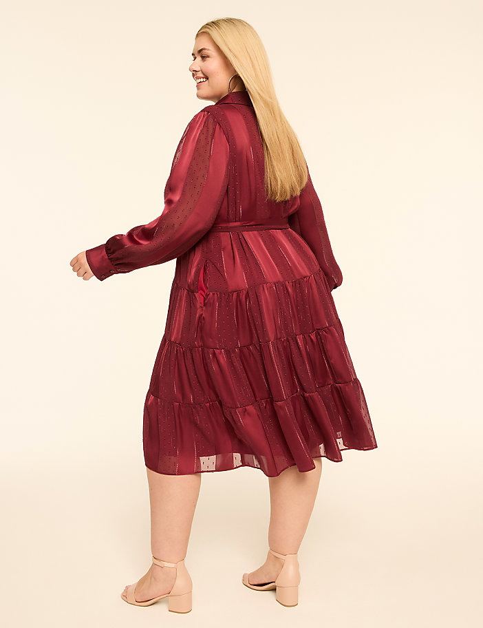 A woman in a burgundy tiered dress and nude heels poses against a plain cream background.