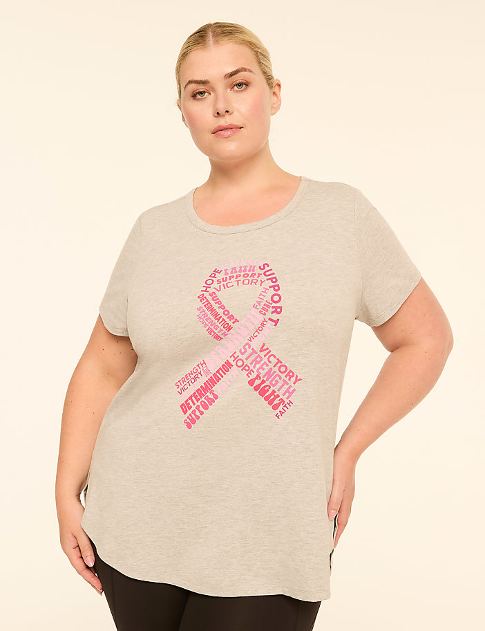 A woman in a grey t-shirt with a pink ribbon made of inspirational words stands against a plain, light background.