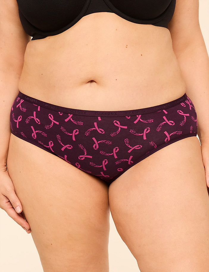 A person wears purple underwear with a pink ribbon pattern in the foreground, against a plain background.