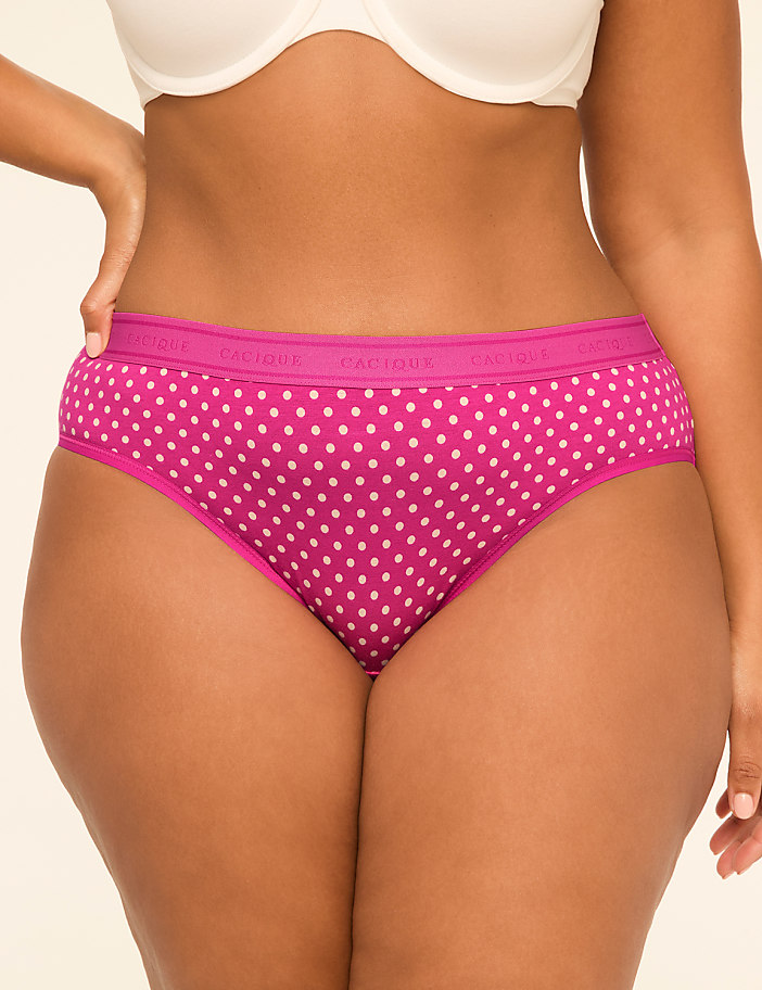 A woman's torso is shown from the waist down, wearing pink polka dot underwear and a white bra, against a plain background.
