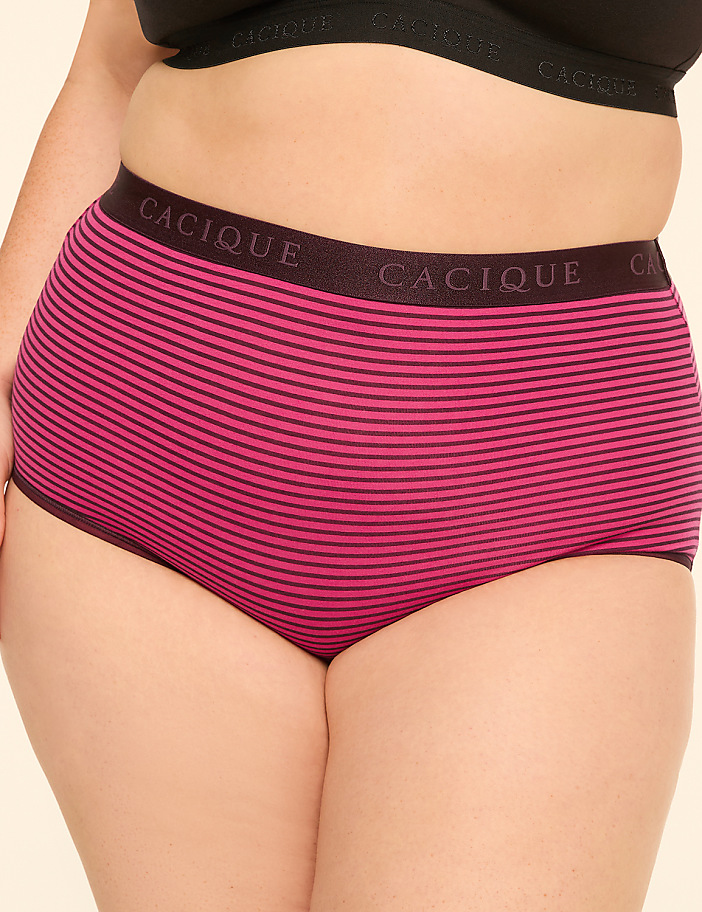 A person in a black bra wears pink and black striped high-waisted underwear against a plain background.