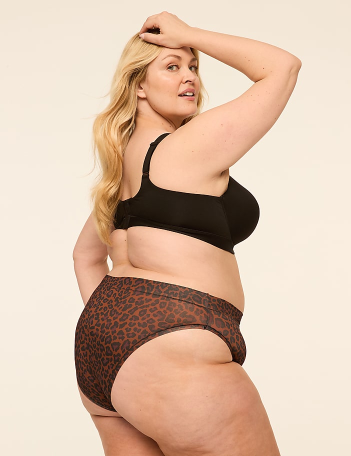 A woman with blonde hair and a leopard-print bottom is posing against a plain, light-colored background.