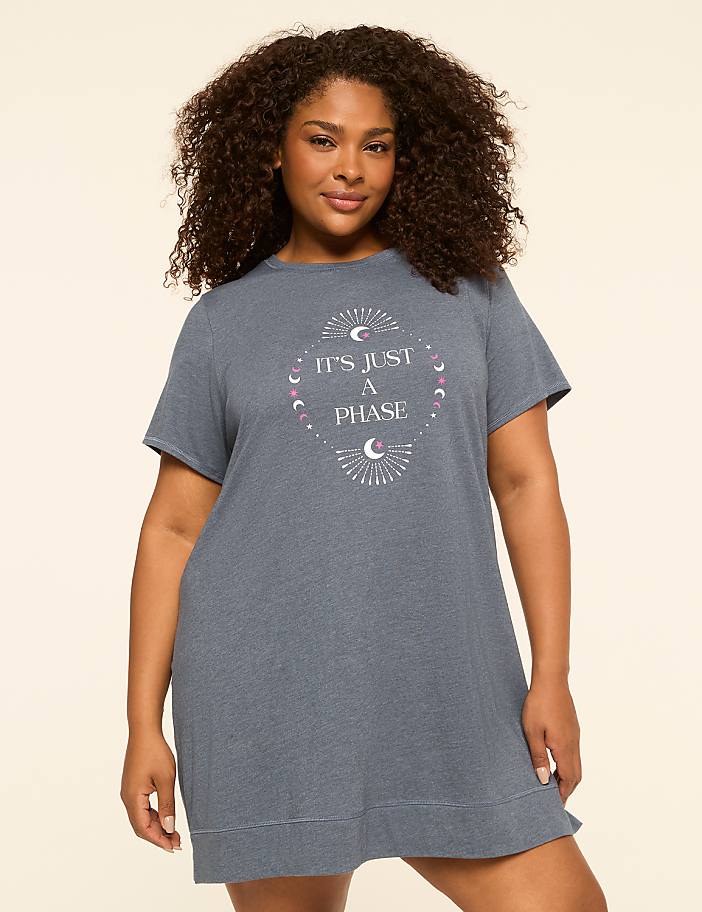 A woman in a blue t-shirt dress with a celestial graphic stands against a plain, light-colored background.