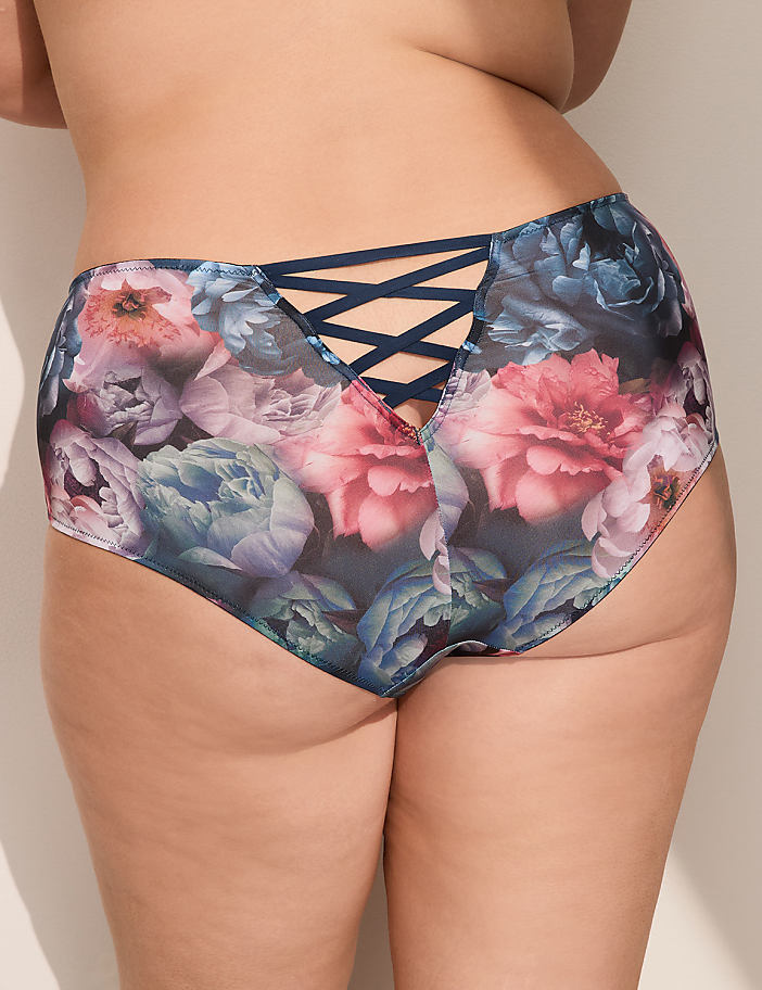A close-up of a person's posterior is shown, wearing floral-patterned underwear with a criss-cross detail in the back, against a plain, light-colored background.