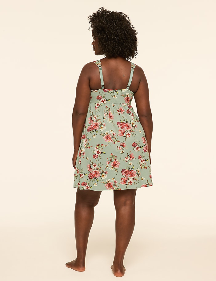 A woman in a floral dress stands with her back to the camera against a plain, light-colored background.