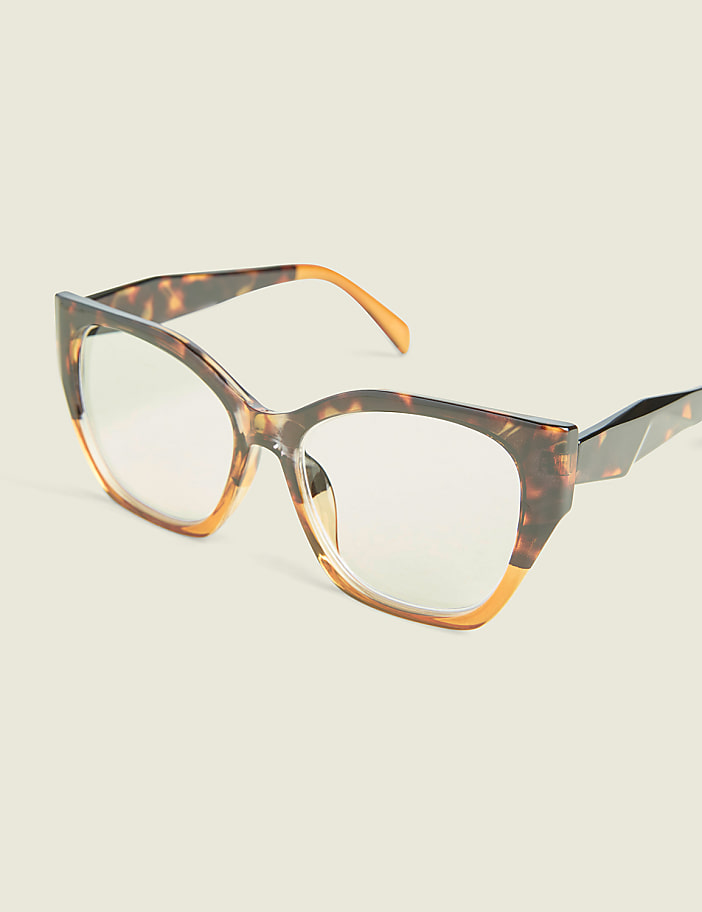 Tortoiseshell cat-eye glasses with clear lenses rest on a plain, light-colored background.