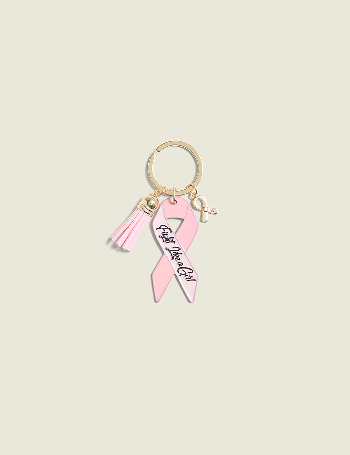 A pink breast cancer awareness ribbon keychain with a tassel and a small ribbon charm hangs against a plain, light beige background.