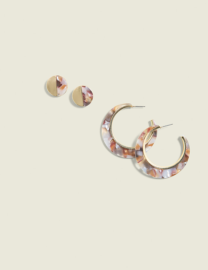 Two pairs of earrings, one stud and one hoop, with marbled patterns are arranged on a pale, textured background.