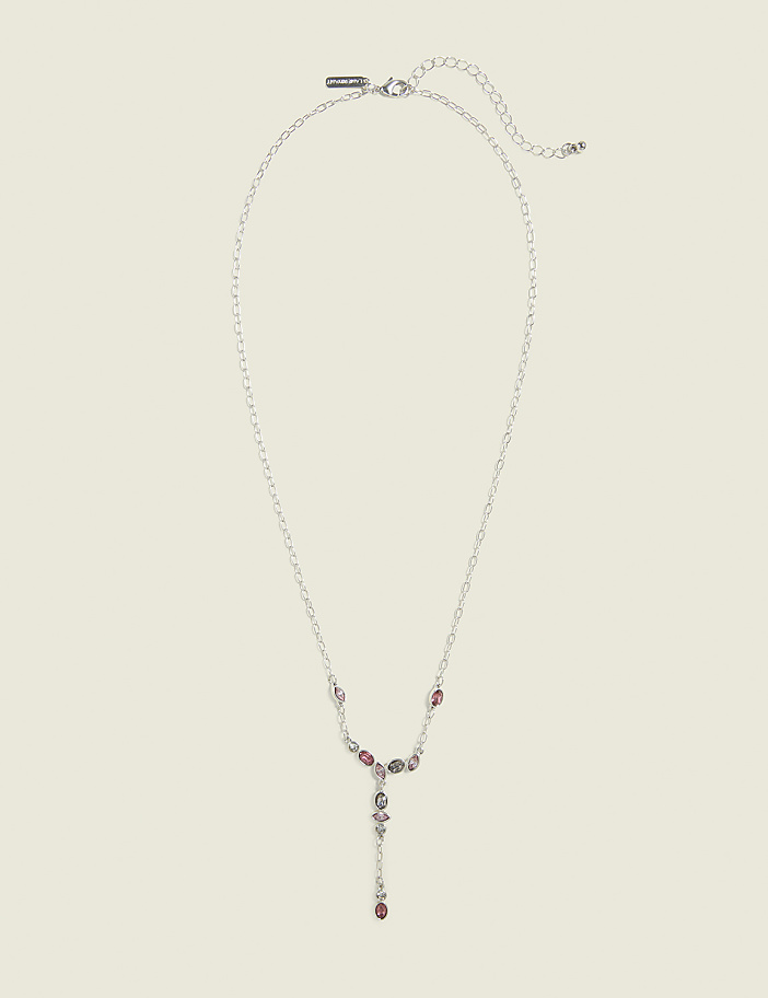 A delicate silver necklace with colorful gemstones hangs against a plain, light-colored background.