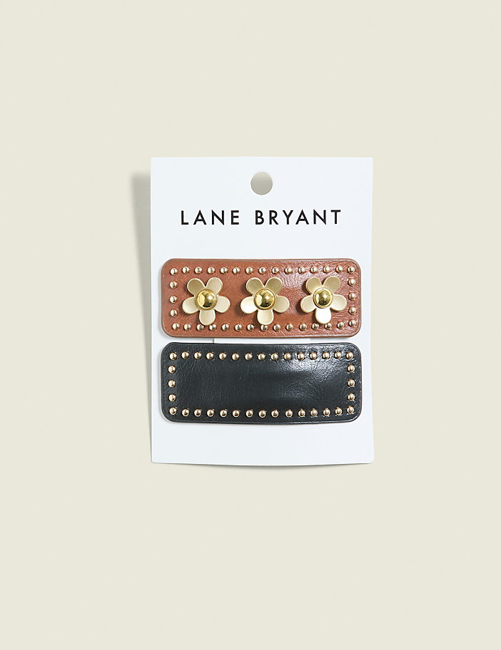 Two decorative hair clips, one brown with gold flowers and the other black with gold studs, are displayed on a white card against a pale gray background.
