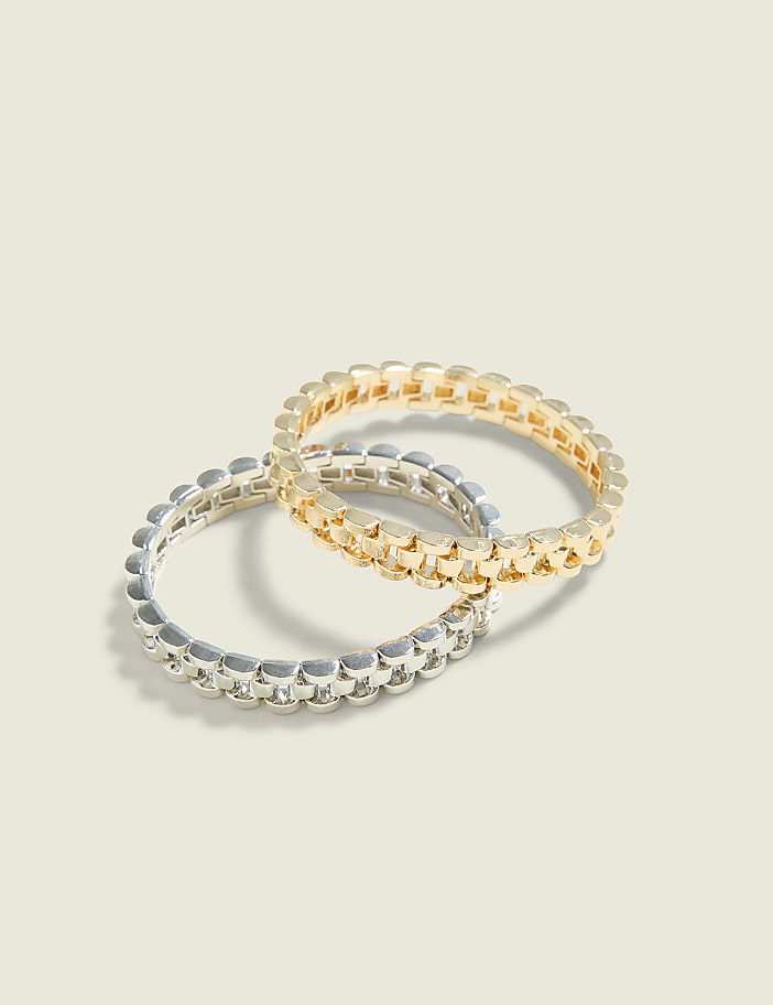 Two interlocking chain-link rings, one gold and one silver, rest on a plain, light-colored background.