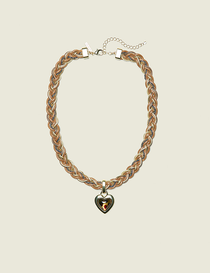 A braided gold and silver necklace with a heart-shaped pendant rests against a plain, light-colored background.