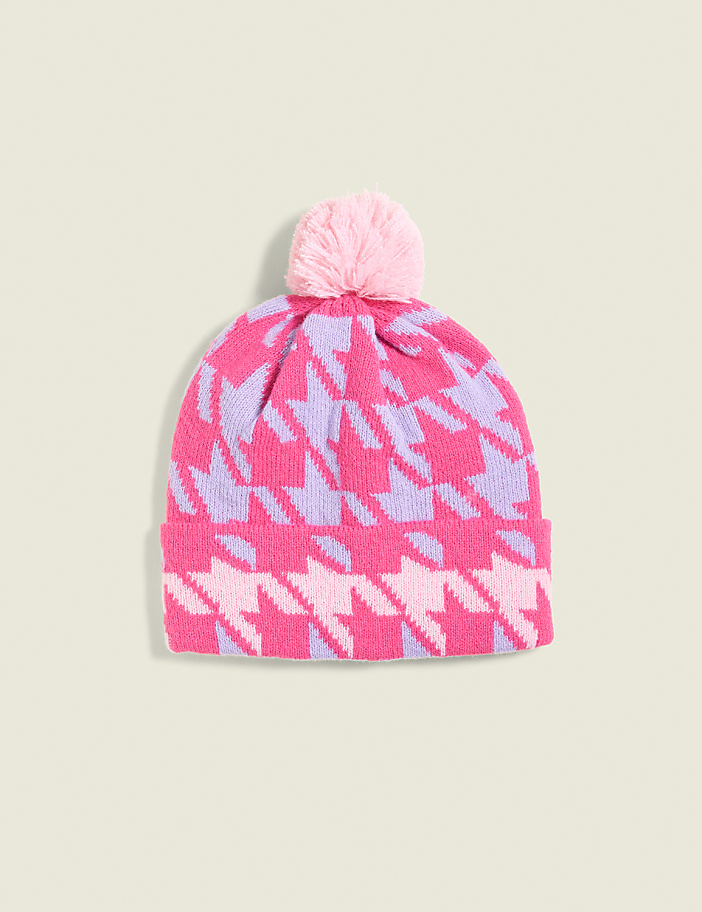 A pink and purple houndstooth knit beanie with a light pink pom-pom sits against a pale green background.