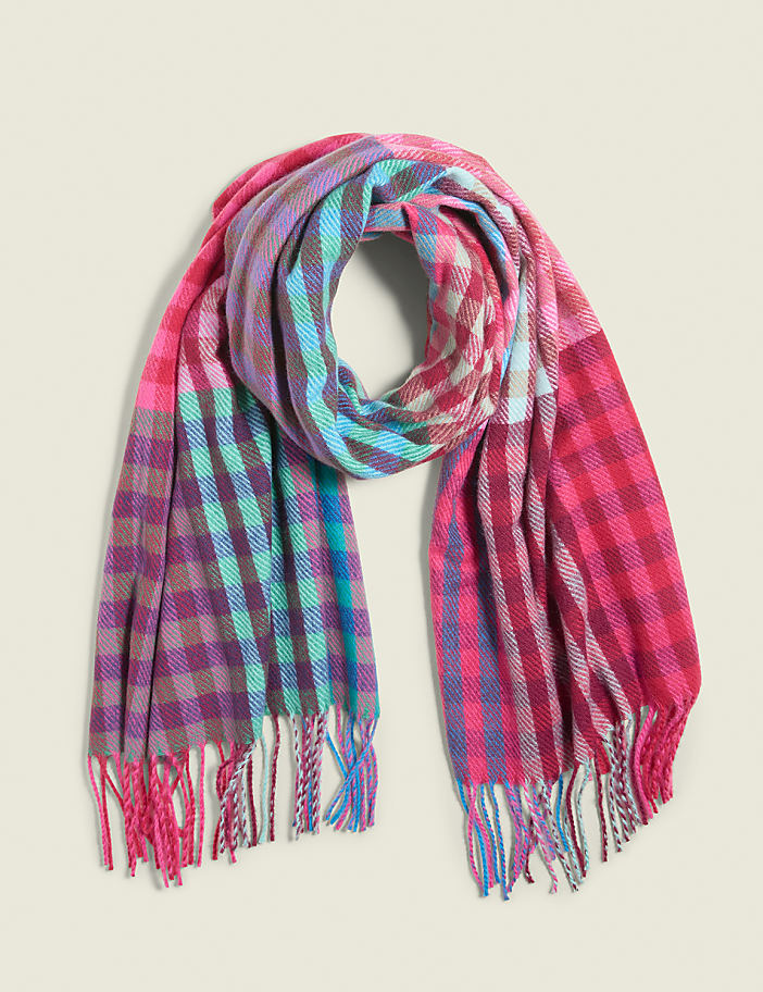 A colorful, plaid scarf with fringed ends is laid out against a plain, light-colored background.