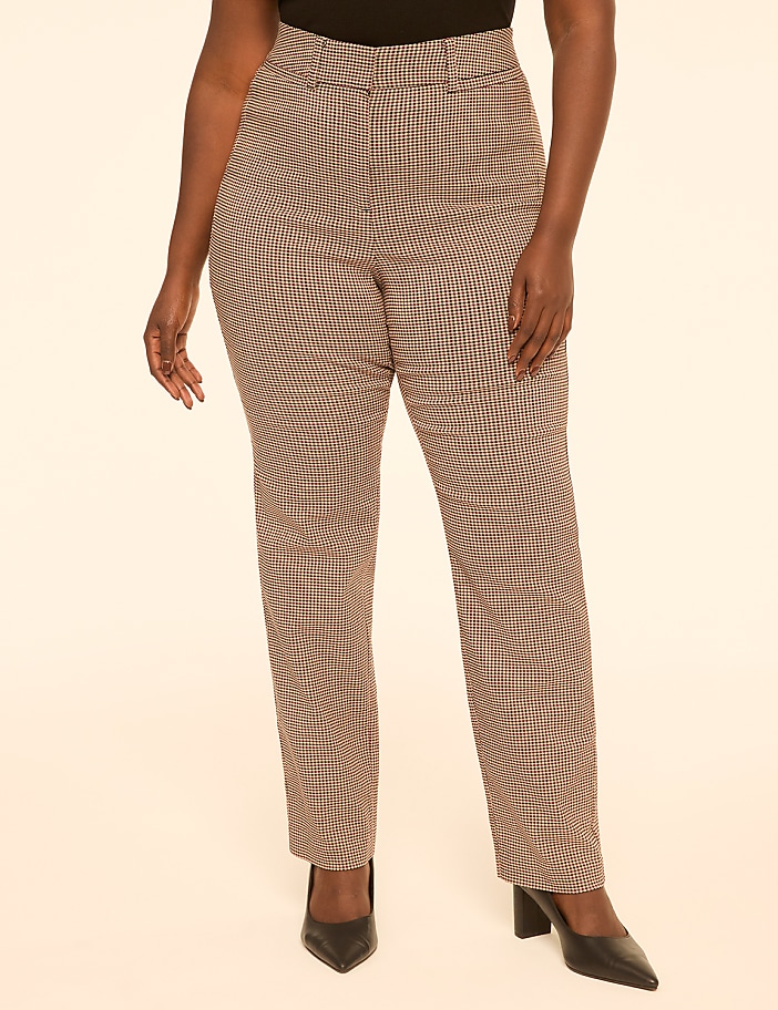A person stands in the foreground wearing plaid pants and black heels against a plain, light-colored background.