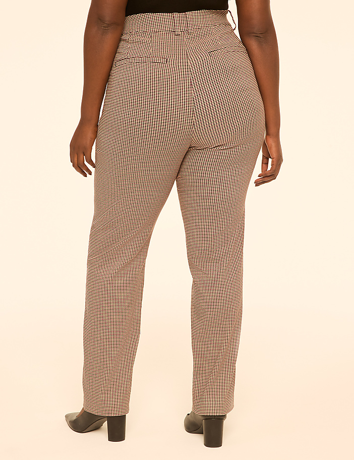 A person wearing brown and white checkered pants and black heels stands against a plain cream background.