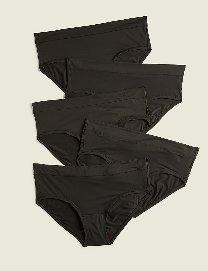 Several black briefs are neatly arranged in the foreground against a plain, light beige background.