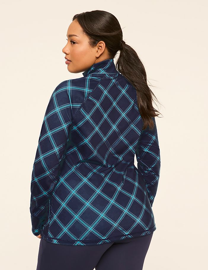 A woman in a blue plaid jacket stands against a plain, light-colored background.