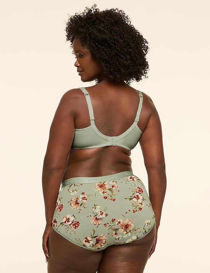 A woman in a floral bra and high-waisted underwear stands against a plain, light-colored background.