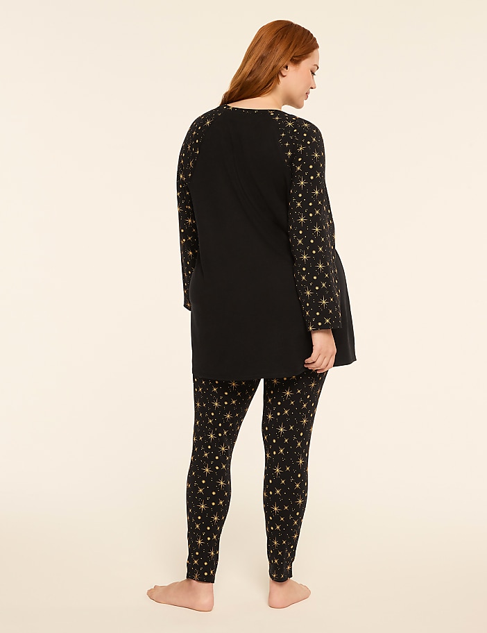 A woman in a black star-patterned pajama set stands against a plain, light-colored background.