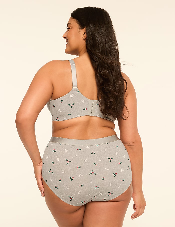 A woman in a grey, holly-patterned bra and underwear stands against a plain, light-colored background.