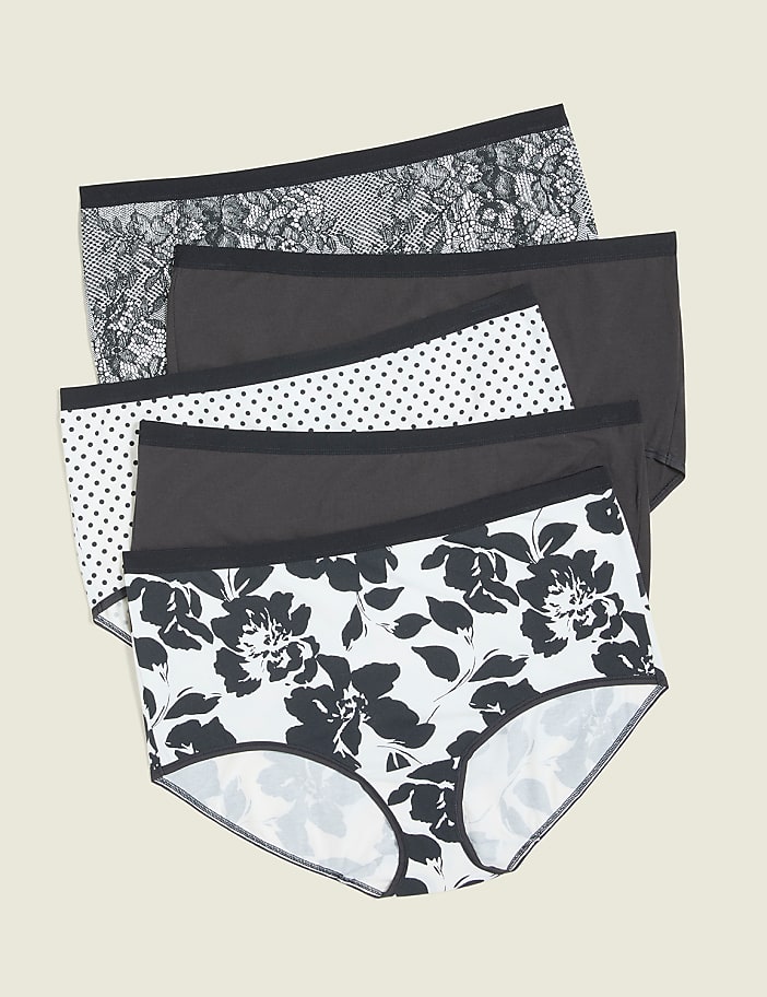 Four pairs of patterned underwear are stacked in the foreground against a plain, light-colored background.