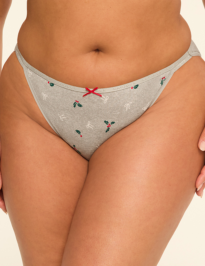 A close-up of a person's lower torso in grey underwear with a festive bow pattern, against a plain background.