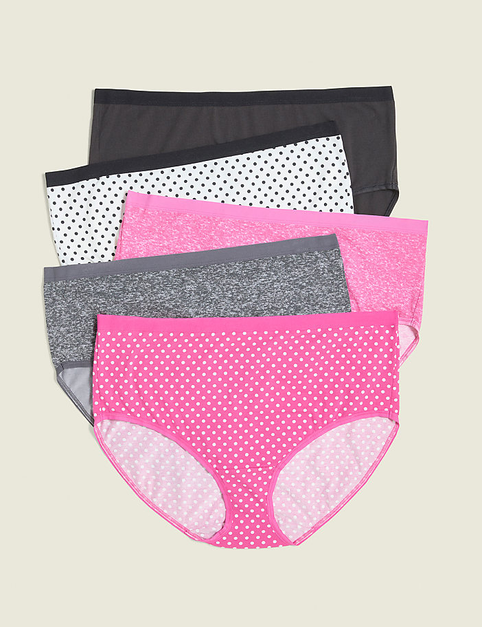 Four pairs of women's underwear, featuring polka dots and solid colors, are neatly stacked against a plain, light beige background.