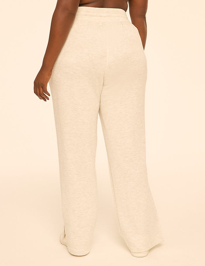 A person wearing light-colored sweatpants stands against a plain, light-colored background.