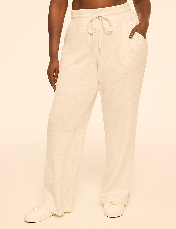 A person stands in light-colored sweatpants with pockets and a drawstring, against a plain, light-colored background.
