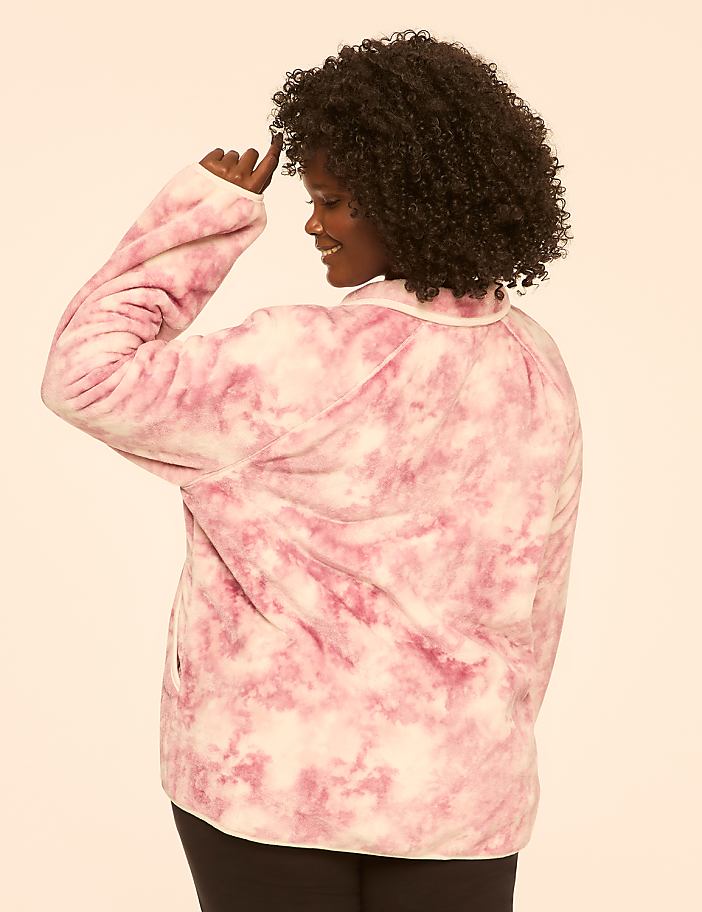 A woman in a pink tie-dye jacket stands against a plain, light-colored background.