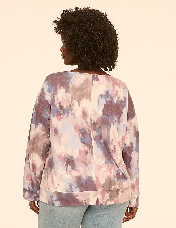 A woman wearing a colorful, abstract-patterned sweatshirt is shown from the back against a plain, light-colored background.