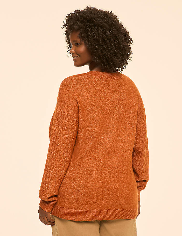 A woman in a rust-colored sweater is shown from the back against a plain, light peach background.