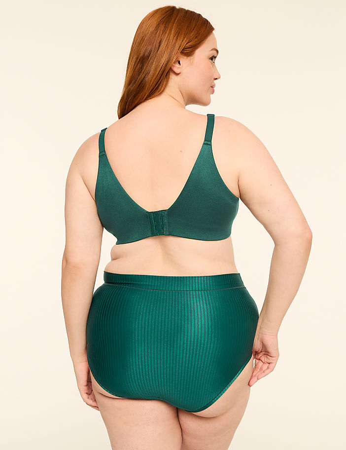 A woman with auburn hair is shown from the back, wearing a green bra and high-waisted underwear against a plain, light-colored background.