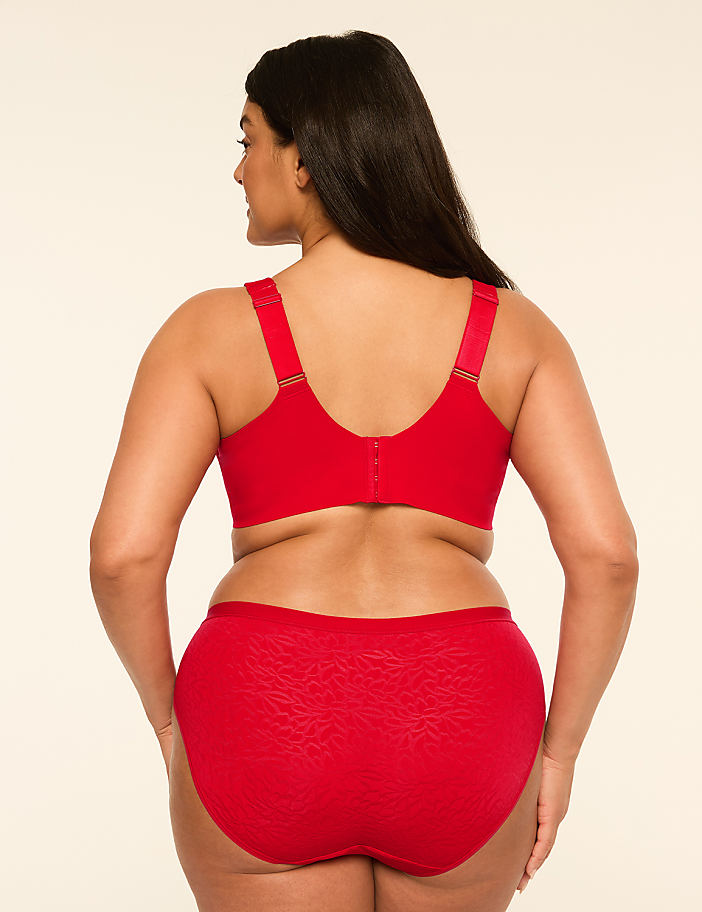 A woman in red lingerie stands against a plain, light-colored background.
