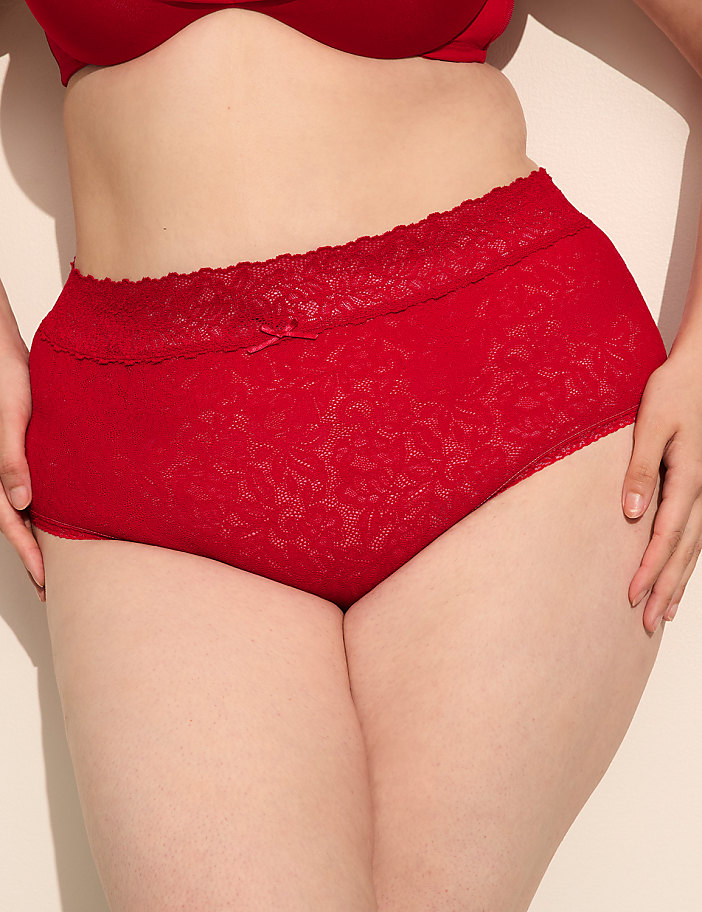 A person wears red lace underwear in the foreground, with a plain background.