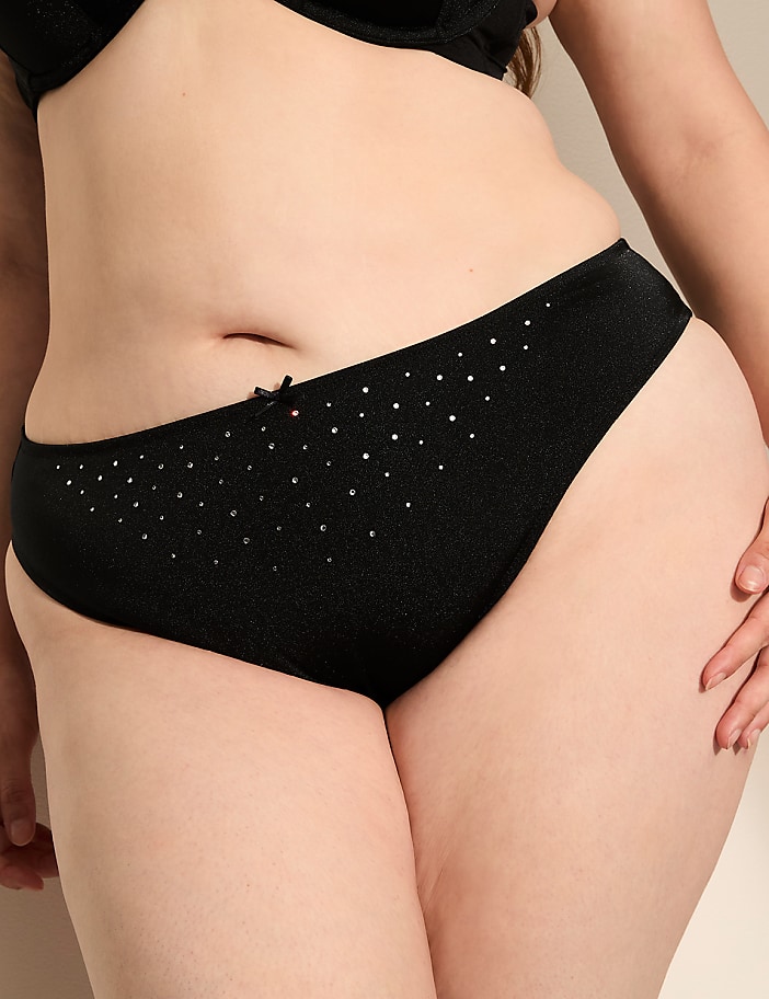 A close-up of a person's torso in black underwear with a subtle sparkle, against a plain background.