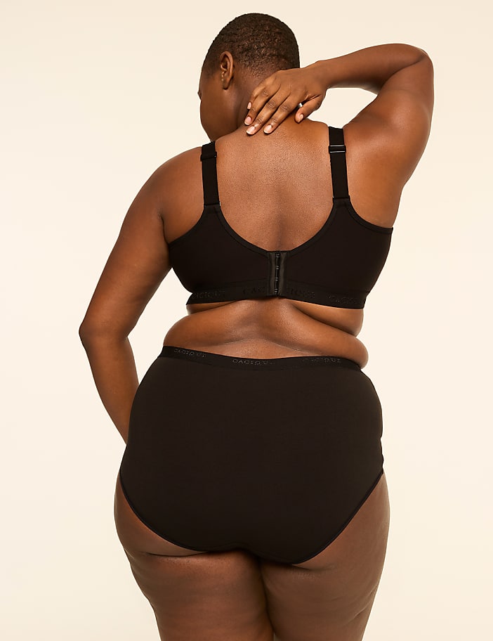 A person in black underwear stands with their back to the viewer against a plain, light-colored background.